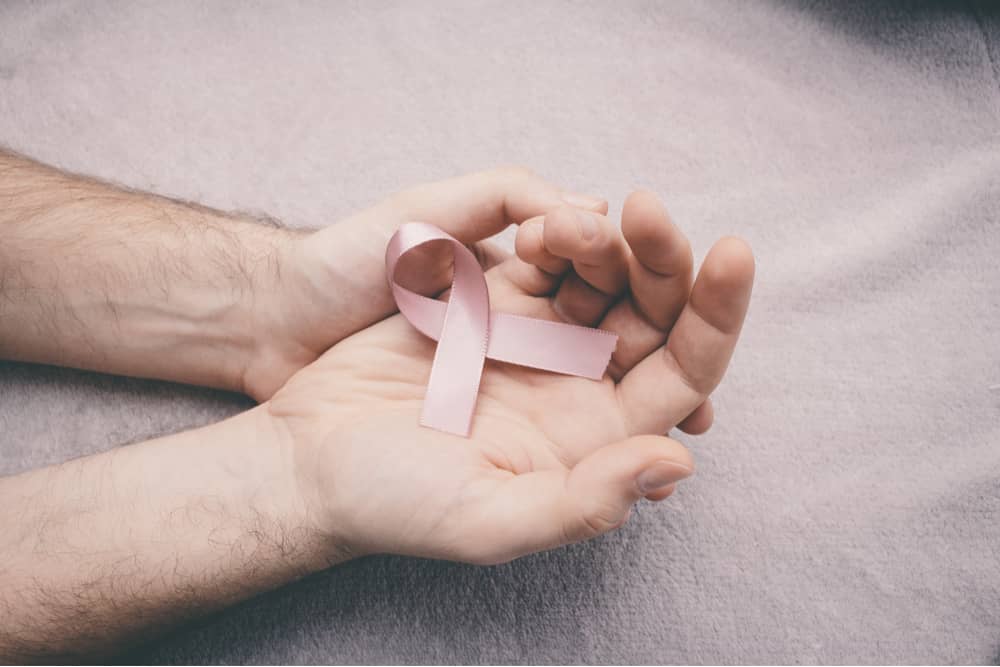 hands holding pink october ribbon