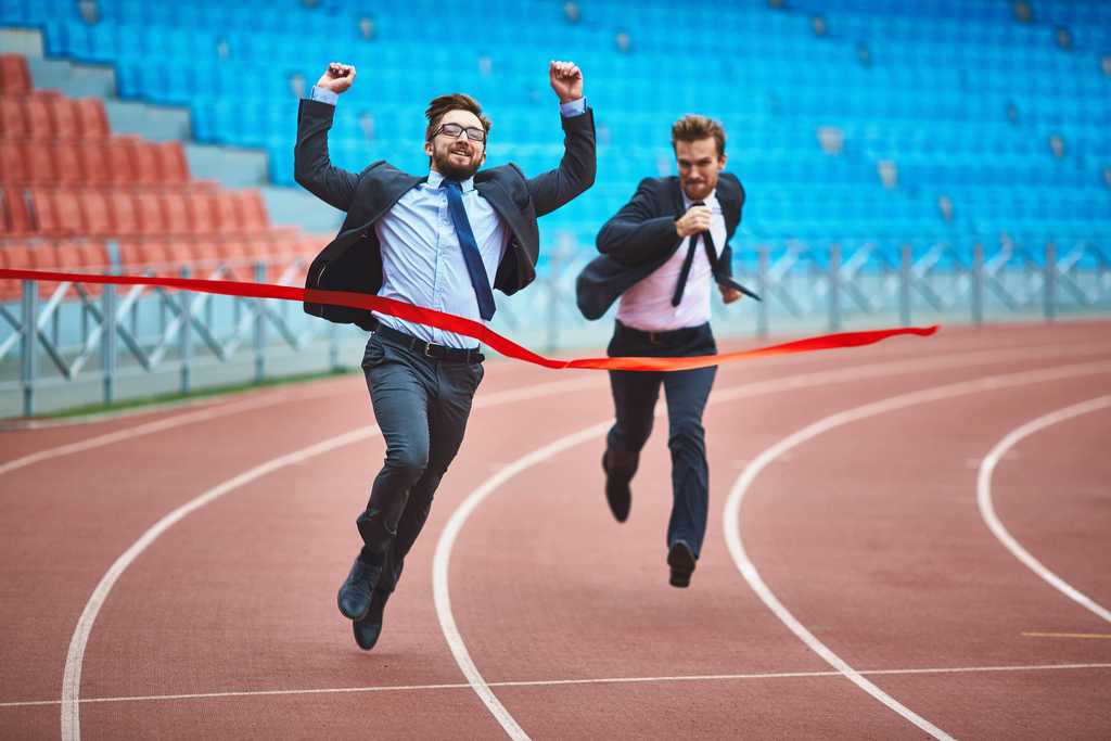 Two men in suits going throw a finish line