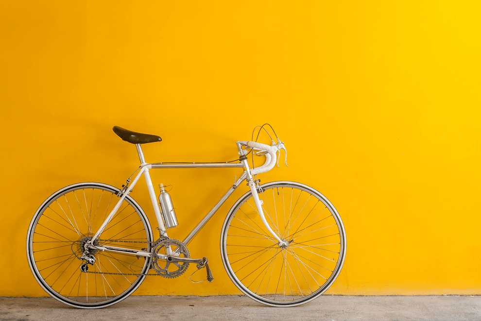 Bicycle resting on a yellow wall