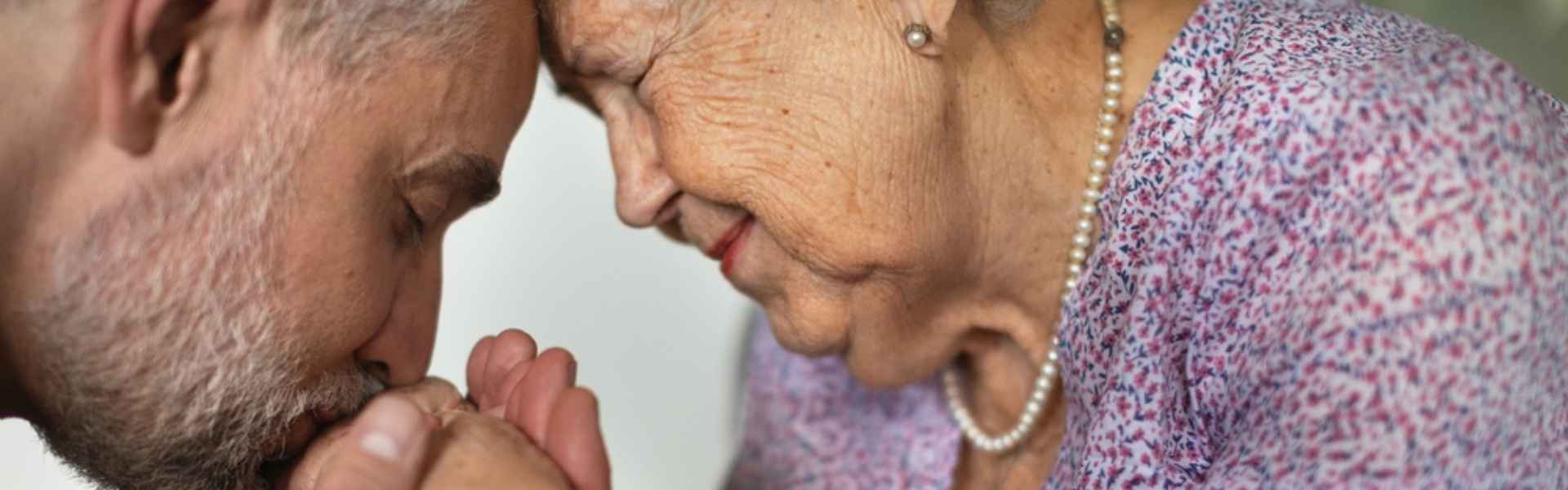 adult man kissing his senior mother's hand