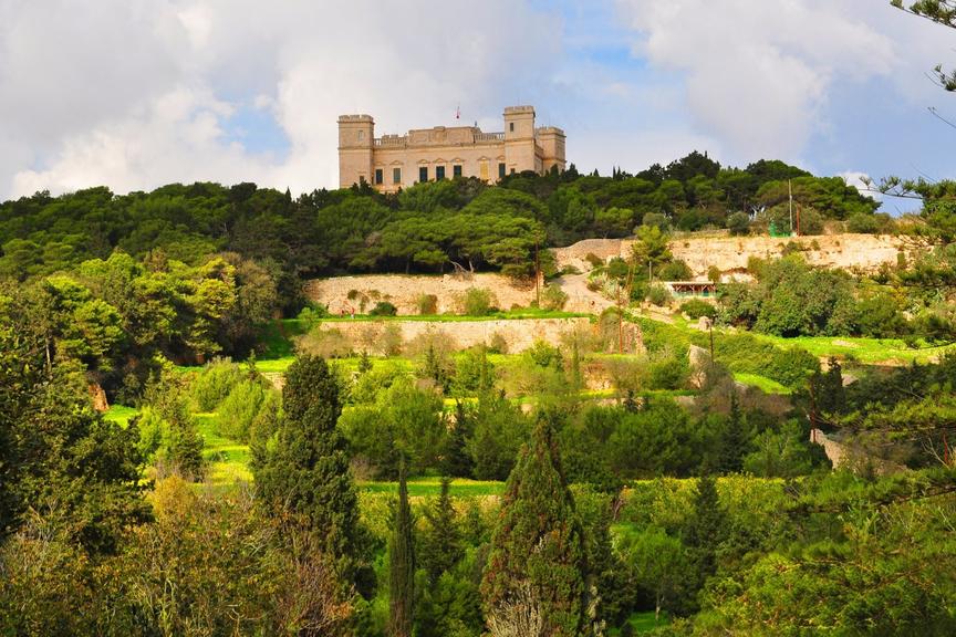 Verdala Palace, a 16th-century sandstone castle, rising above lush terraced gardens and dense pine woodland in the Buskett area of Malta