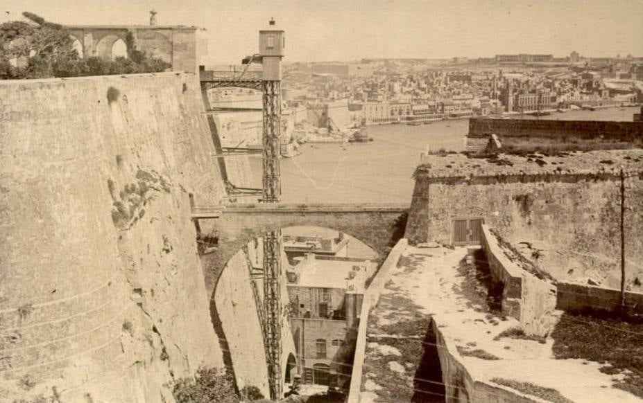a lift attached to Valletta fortifications with the harbour in the background